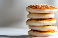 Stack of fresh white fluffy pancakes with golden brown tops on light background, close up view showing soft texture and layers for food photography.