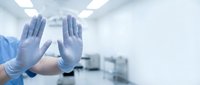 Healthcare professional wearing protective gloves with raised hands in sterile medical environment showing safety protocols and hygiene standards.