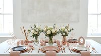 Elegant dining table setting with copper accents, white roses and eucalyptus centerpieces for special occasions and entertaining guests.