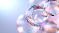 Macro photography of transparent soap bubbles floating in air with soft pink and blue bokeh background creating dreamy atmospheric effect.