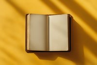 Open blank notebook with brown leather cover on yellow background with dramatic diagonal shadow, minimalist composition for creative writing and journaling.