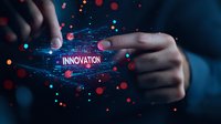 Hands manipulating glowing innovation text with digital particles and light effects in dark blue atmosphere, representing technological advancement and future concepts.