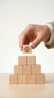 Hand placing a wooden block with paw print symbol on top of a pyramid stack, representing pet care, animal services, or veterinary business growth.