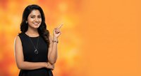 Young Indian businesswoman pointing finger up with confident smile on orange gradient background for presentations and marketing materials.