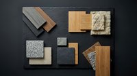 Interior design material samples including wood flooring, stone tiles, granite countertops and textured surfaces arranged on dark background for renovation planning.
