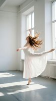 Young Caucasian female ballet dancer in white dress performing graceful arabesque in sunlit studio, flowing hair and skirt in motion.