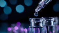 Clear liquid drop falling from glass dropper into medical vial on dark background with purple and blue bokeh lights, pharmaceutical research concept.
