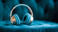 Wireless headphones with blue ear cups and white headband resting on fabric surface, suitable for music, audio, and technology marketing materials.