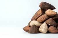 Fresh brazil nuts in shell pile on white background, showing natural organic texture and varying shades of brown, suitable for healthy eating and nutrition concepts.