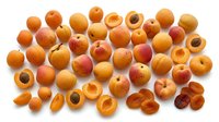 Fresh apricots and dried apricot halves scattered on white background, organic stone fruit collection for healthy eating and cooking recipes.