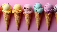 Colorful ice cream scoops in waffle cones arranged in row on pink background. Variety of flavors including vanilla, strawberry, mint and chocolate chip create sweet dessert composition.
