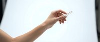 Woman hand holding small metal paper clip against white background for office supplies and organization concepts.