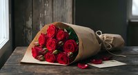 Red roses bouquet wrapped in brown kraft paper on rustic wooden table near window. Romantic gift for Valentine's Day, anniversary or special occasion.
