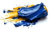 Vibrant blue and yellow oil paint smeared on white surface showing rich texture and artistic brush strokes, demonstrating color mixing and painting technique.