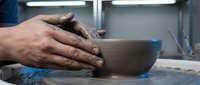 Artisan hands shaping clay on pottery wheel in studio workshop, creating ceramic vessel with traditional craftsmanship technique and skill.