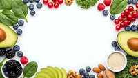 Healthy superfood frame with fresh berries, avocado, nuts and greens on white background. Nutritious organic ingredients for clean eating lifestyle.