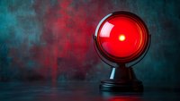 Glowing red warning light on dark textured background with dramatic lighting and reflection. Surveillance and security concept for technology designs.