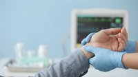Healthcare professional in blue gloves examining elderly patient's hand in modern medical office setting for diagnostic consultation.