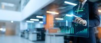 Professional businessman analyzing digital financial data with holographic interface displaying charts and graphs in modern office environment.