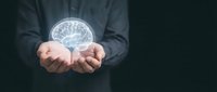 Businessman in dark suit holding glowing brain hologram in cupped hands, representing artificial intelligence, innovation, and digital technology solutions for business.