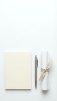 Elegant cream notebook with silver pen and white scroll tied with natural ribbon on clean white background for stationery and office design projects.
