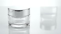 Empty glass cosmetic jar with silver lid on white background for skincare product packaging and beauty brand marketing.