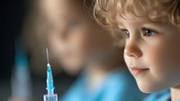 Young Caucasian boy with curly blonde hair looking curiously at medical syringe with blue liquid, vaccination concept in soft focus lighting for healthcare awareness.