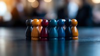 Colorful wooden game pieces arranged in row showing diversity and teamwork concept on dark surface with blurred bokeh background. For business presentations.