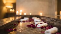 Luxury spa bathtub with floating candles and rose petals in warm ambient lighting creating relaxing wellness atmosphere for self-care and rejuvenation.