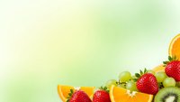 Fresh fruit salad with strawberries, kiwi, orange slices and grapes on soft gradient background for healthy eating and nutrition concepts.