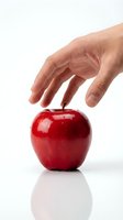 Hand reaching toward shiny red apple on white background. Isolated fruit ready for health, nutrition, diet, and wellness design projects.