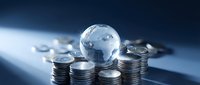Global economy concept with crystal earth globe surrounded by stacks of silver coins on dark blue background for business and finance presentations.