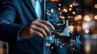 Asian businessman analyzing digital financial charts and market data on futuristic transparent display with glowing bokeh lights in dark office environment.
