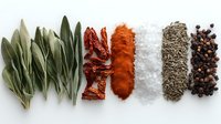Fresh sage leaves, dried chili peppers, paprika powder, sea salt, cumin seeds and black peppercorns arranged in neat rows on white background, culinary spices composition.