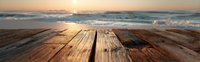 Wooden dock or pier at sunset with ocean waves and golden horizon, creating serene coastal atmosphere for vacation, relaxation, and travel themes.