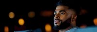 Young African American man with beard smiling confidently against blurred city lights background at night, professional headshot for business and lifestyle content.