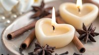 Heart shaped cream candles burning with cinnamon sticks and star anise on ceramic plate, romantic spa aromatherapy composition in soft focus for wellness and relaxation.