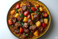 Savory beef stew with tender meat chunks, colorful bell peppers, potatoes, and fresh herbs served over golden noodles in traditional ceramic bowl on light surface.