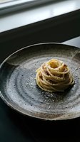 Elegant spaghetti carbonara with egg yolk, crispy pancetta, and pecorino on a rustic ceramic plate, dark moody food photography.