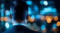 Rear view of male professional wearing business suit and headphones against blurred urban cityscape with bokeh lights, suitable for corporate, technology, and communication concepts.