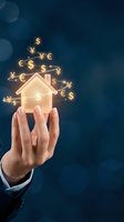 Hand holding glowing house icon with floating currency symbols for real estate investment and property finance concepts on dark blue background.