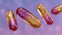 Glowing pharmaceutical capsules with golden and pink sparkles floating on purple background, medical concept for healthcare and medicine innovation.