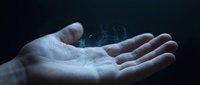 Open palm holding glowing digital network connections with light particles floating above hand against dark background for technology concepts.
