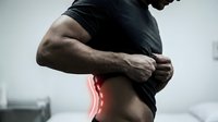 Athletic man experiencing lower back pain during workout, highlighting sports injury and muscle strain for health and fitness awareness.