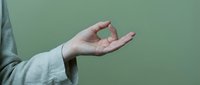Caucasian male hand in light gray sleeve gesturing open palm against muted green background, suitable for business communication, web design, and instructional materials.