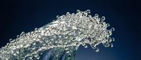 Dynamic water wave splash with sparkling droplets frozen in motion against a deep blue background, capturing fluid energy and natural beauty.