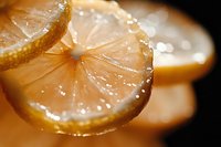Fresh lemon slice with water drops and bubbles on golden background, macro photography showing juicy citrus texture and translucent pulp segments.
