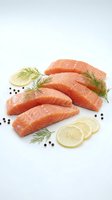 Fresh salmon fillets with lemon slices and dill herbs on white background, raw fish portions ready for cooking, healthy seafood ingredient for culinary preparation.