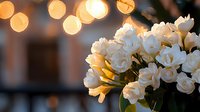 White roses bouquet against blurred warm bokeh lights background creates romantic atmosphere for wedding, anniversary or special occasion celebration.