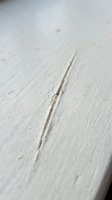 Close-up of a crack running diagonally across a light wooden surface with visible grain texture and weathered finish, suitable for backgrounds and design projects.